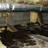 Fiberglass insulation dripping off a floor joist in a soaked crawl space with a think black liner in Dover.
