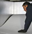 A contractor installing TerraBlock™ floor insulation in a Rehoboth Beach crawl space
