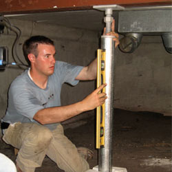 A contractor in Hockessin installing a crawl space jack post.